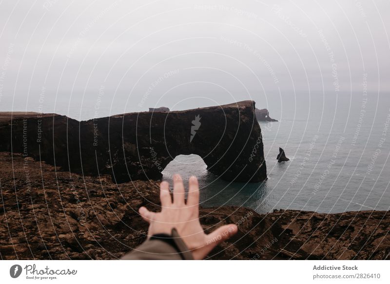 Ernte von Hand bis zum Ozean ausgestreckt Mann Felsen Meer Island Höhe Landschaft Aussicht Küste trist extrem Seeküste Abenteuer Natur Berge u. Gebirge Wildnis