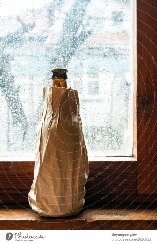 Flasche mit Alkohol in einem braunen Packpapier, das an das Fenster gestellt wird. Getränk Bier Papier Paket gelb Alkoholsucht umhüllen Tasche Hintergrund Party