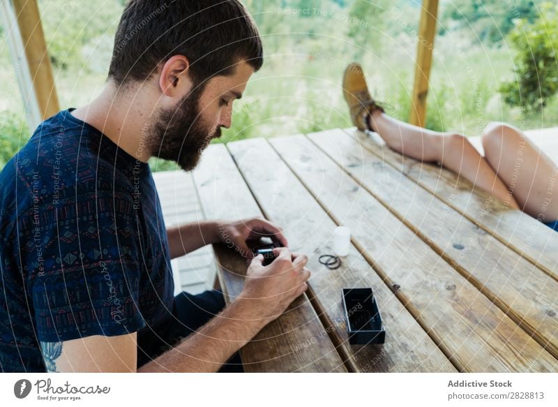 Junger Mann bringt neuen Film in die Kamera. Rolle Fotoapparat Fotograf Natur Kreativität retro Filmmaterial Fotokamera altehrwürdig Technik & Technologie Tisch