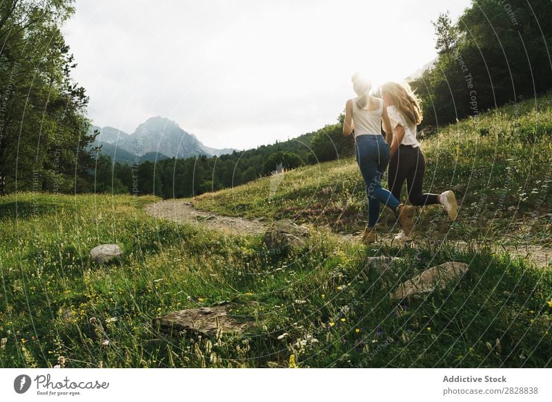 Fröhliche Frauen, die auf der Bergstraße laufen. Straße ländlich Freundschaft Rucksack Natur Mädchen Jugendliche schön Ferien & Urlaub & Reisen Tourismus