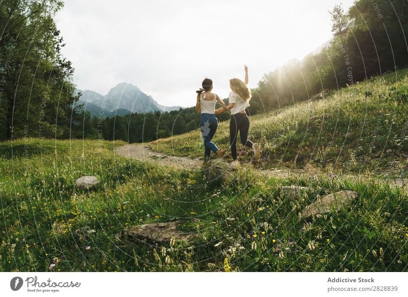 Fröhliche Frauen, die auf der Bergstraße laufen. Straße ländlich Freundschaft Rucksack Natur Mädchen Jugendliche schön Ferien & Urlaub & Reisen Tourismus