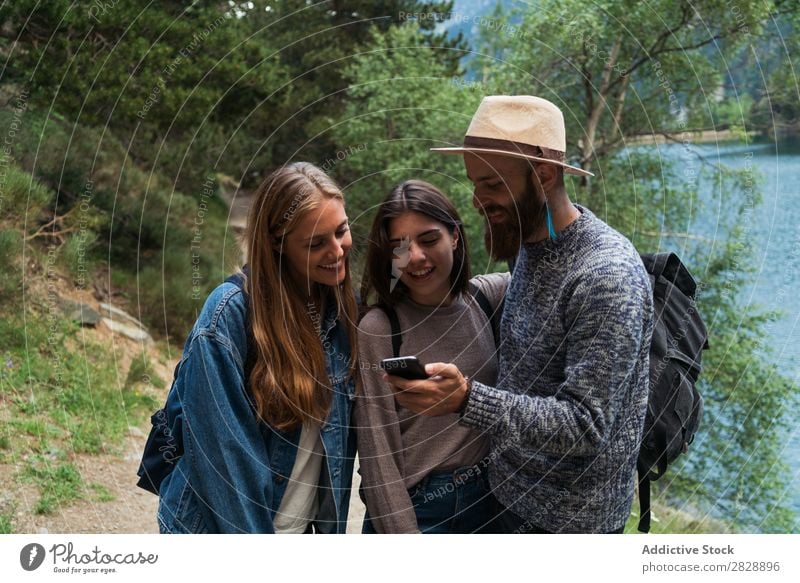 Freunde mit Telefon in den Bergen Frau Mann Berge u. Gebirge laufen PDA benutzend Browsen Zusammensein Lächeln wandern See Wasser heiter Glück