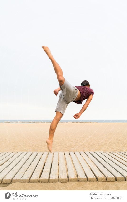 Mann, der Sprünge am Strand übt. springen Sport Flip üben Fitness Freiheit Gleichgewicht Pose Kraft Energie Athlet lässig Sonnenuntergang Training muskulös