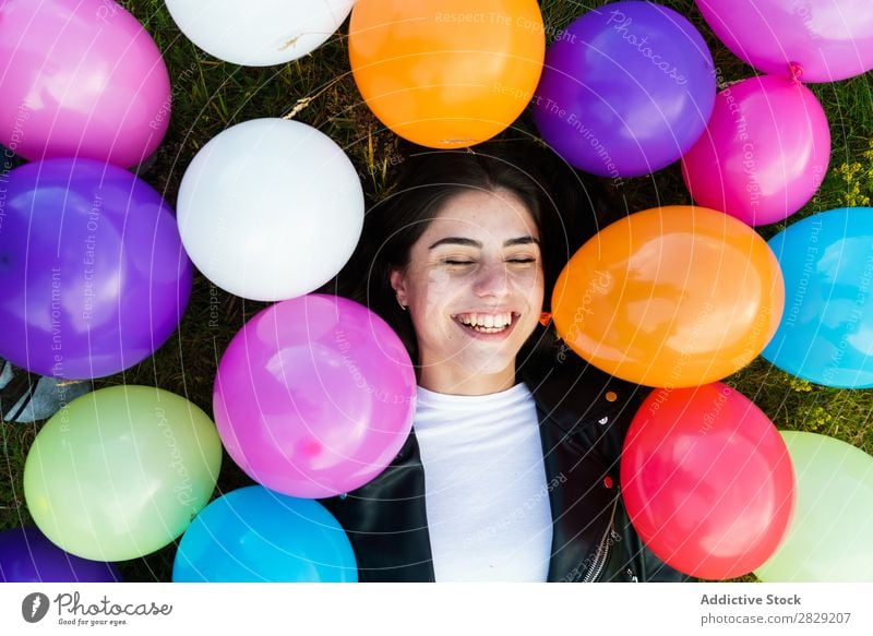 Hübsche Frau, die in Luftballons liegt. Natur hübsch Körperhaltung lügen Gras Ballons Lächeln lachen Freiheit Freude schön Mensch Beautyfotografie Fröhlichkeit