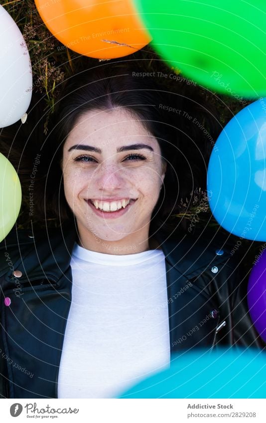 Hübsche Frau, die in Luftballons liegt. Natur hübsch Körperhaltung lügen Gras Ballons Lächeln lachen Freiheit Freude schön Mensch Beautyfotografie Fröhlichkeit