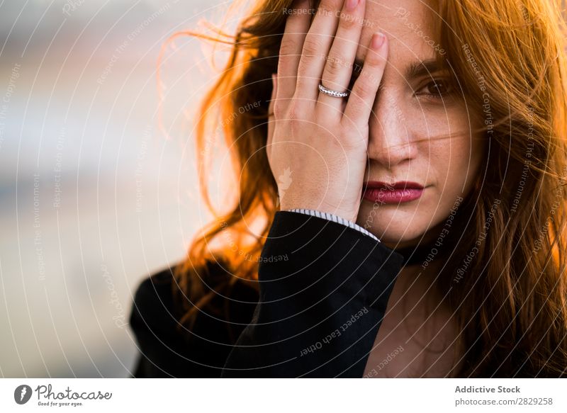 Frau, die das Gesicht mit der Hand schließt. selbstbewußt Auge schließen Sonnenuntergang Blick in die Kamera lässig Bekleidung Stil ernst Jugendliche schön