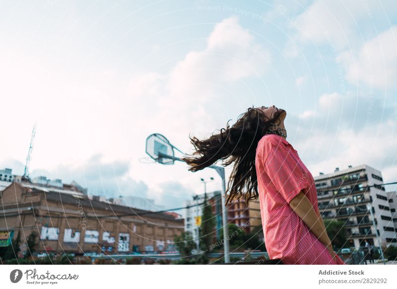 Frau, die auf dem Spielplatz in einem Zaun sitzt. Stil Straße Stadt Körperhaltung Porträt attraktiv Beautyfotografie trendy Lifestyle hübsch Mode Jugendliche