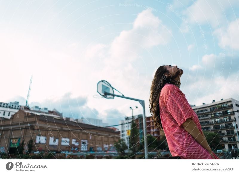 Frau, die auf dem Spielplatz in einem Zaun sitzt. Stil Straße Stadt Körperhaltung Porträt attraktiv Beautyfotografie trendy Lifestyle hübsch Mode Jugendliche