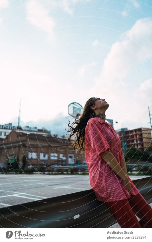 Frau, die auf dem Spielplatz in einem Zaun sitzt. Stil Straße Stadt Körperhaltung Sonnenbrille Porträt attraktiv Beautyfotografie trendy Lifestyle hübsch Mode