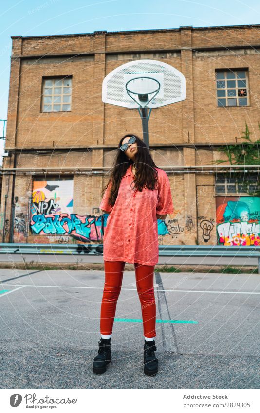 Frau, die auf dem Spielplatz steht. Stil Straße Zaun Stadt Körperhaltung Porträt attraktiv Beautyfotografie trendy Lifestyle hübsch Mode Jugendliche Model schön