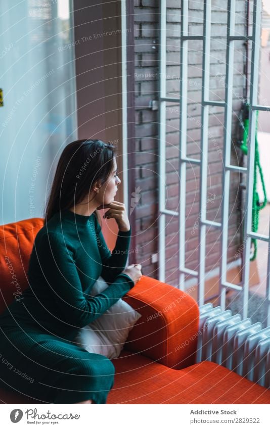 Nachdenkliches romantisches Modell auf dem Sofa Frau Fürsorge träumen Fenster Beautyfotografie Wohnung heimwärts Jugendliche genießen elegant ruhig brünett