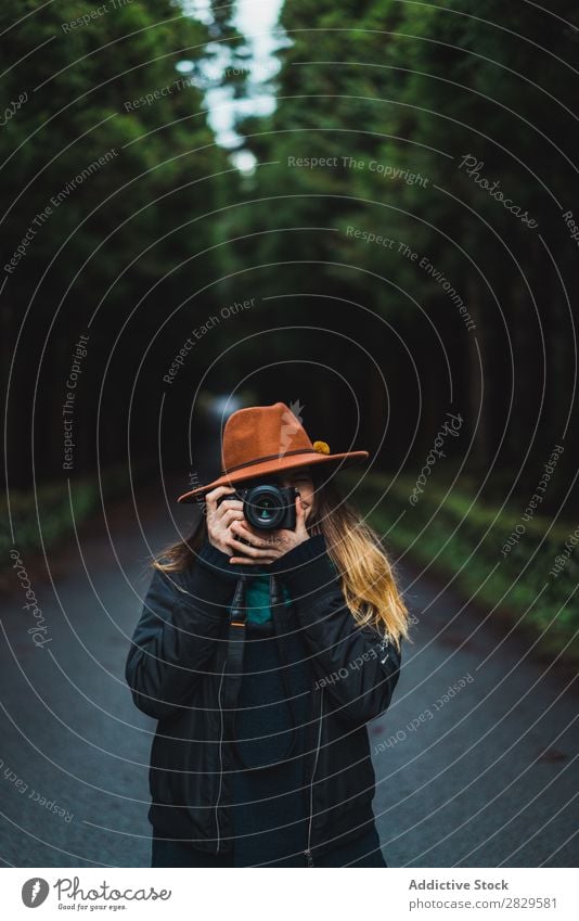 Frau mit Kamera im Wald Fotograf grün Natur Fotokamera Hut hübsch Jugendliche Straße Asphalt Lächeln Umwelt Blick in die Kamera natürlich Jahreszeiten Pflanze