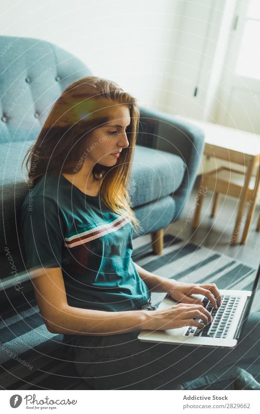 Frau, die den Laptop benutzt, sitzt auf dem Boden. Notebook Wohnung benutzend freiberuflich Tippen Freizeit & Hobby Schüler Etage Technik & Technologie sitzen