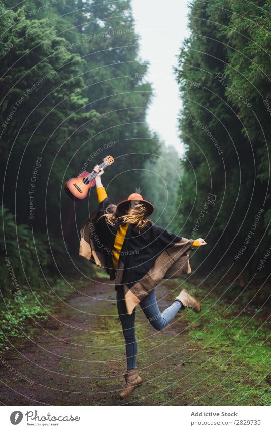 Springende Frau mit Ukulele im Wald Fröhlichkeit Freiheit springen Nebel Reisender Ausdruck Aufregung Bewegung romantisch Energie Ausflug kalt über der Erde