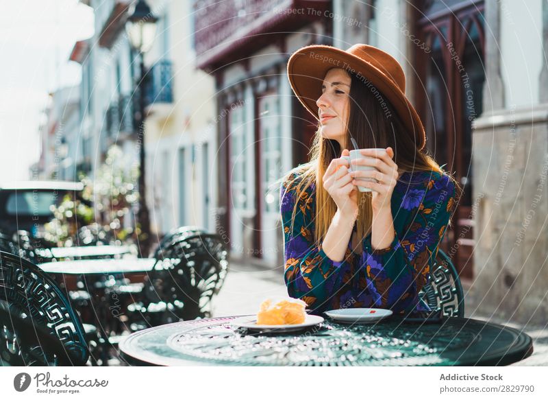 Lächelnde Frau mit Tasse im Außencafé hübsch Stil Straße Hut Kaffee Café Außenaufnahme Mode schön Jugendliche Porträt attraktiv Großstadt Lifestyle Model