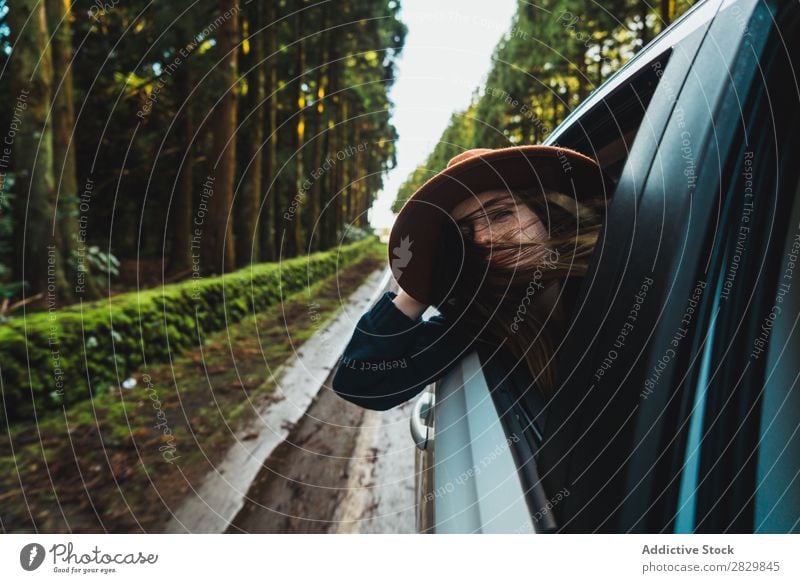 Frau, die im Wald aus dem Auto hängt. PKW Fenster herumhängen grün träumen Hut hübsch Straße Asphalt Natur Umwelt natürlich Jahreszeiten Pflanze Blatt Licht