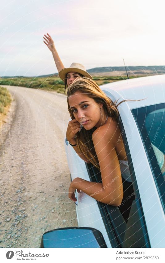 Frauen, die aus dem Auto hängen. PKW Natur Blick in die Kamera hinaushängend Fenster Feld Freude Lifestyle Jugendliche Glück Ferien & Urlaub & Reisen Fahrzeug