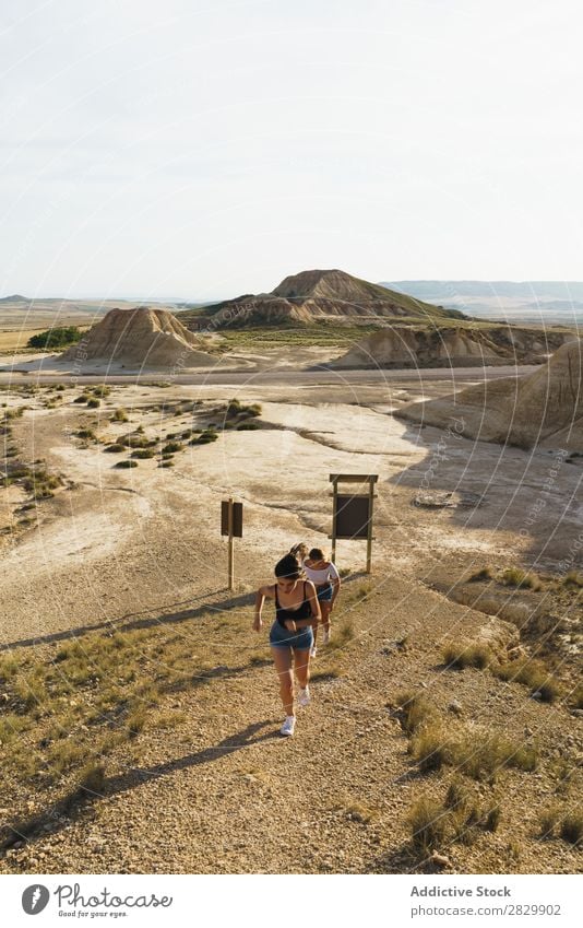 Frauen, die auf einem sandigen Hügel spazieren gehen. laufen Ferien & Urlaub & Reisen Natur Lifestyle Abenteuer wandern Felsen Sand Zeichen Aussicht schön