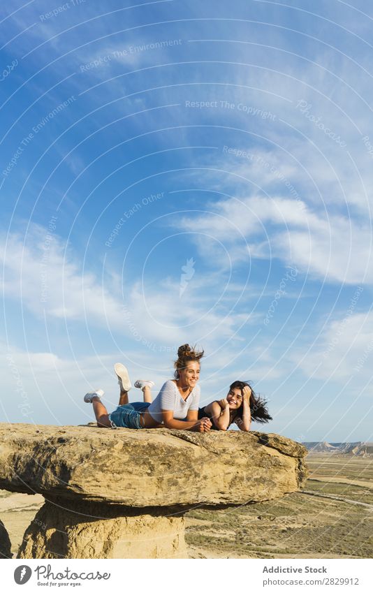 Aufgeregte Frauen, die auf einer Klippe liegen. lügen Erholung Ferien & Urlaub & Reisen Abenteuer Felsen Berge u. Gebirge Tourist Freundschaft Zusammensein