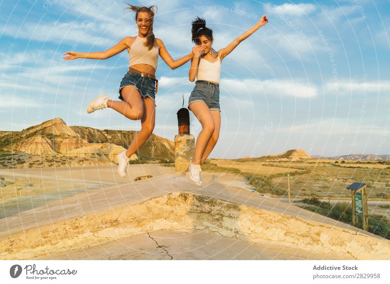 Glückliche Frauen, die auf dem Hügel springen. Klippe Aufregung Händchenhalten Freiheit Ferien & Urlaub & Reisen Erfolg Top Berge u. Gebirge Jugendliche Natur