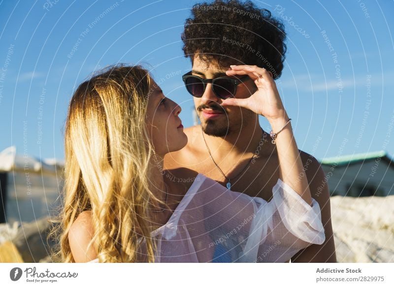 Sanftes Paar, das am Strand posiert. Körperhaltung Stil Meer Flitterwochen Fürsorge Fröhlichkeit Liebe Zusammensein reisend Kulisse Sommer Erholung Sonnenbrille