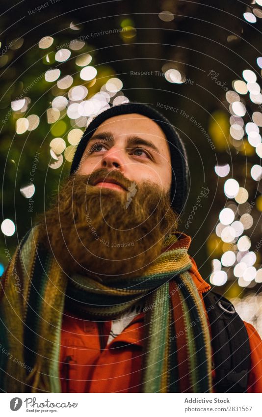 Gutaussehender Mann, der bei Licht posiert. gutaussehend Großstadt Lächeln heiter Illumination Vollbart Hut Straße Jugendliche Stadt Lifestyle lässig Mode Stil