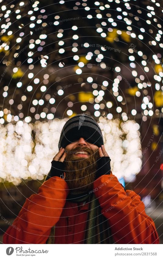 Gutaussehender Mann, der bei Licht posiert. gutaussehend Großstadt Lächeln heiter Illumination Vollbart Hut Straße Jugendliche Stadt Lifestyle lässig Mode Stil