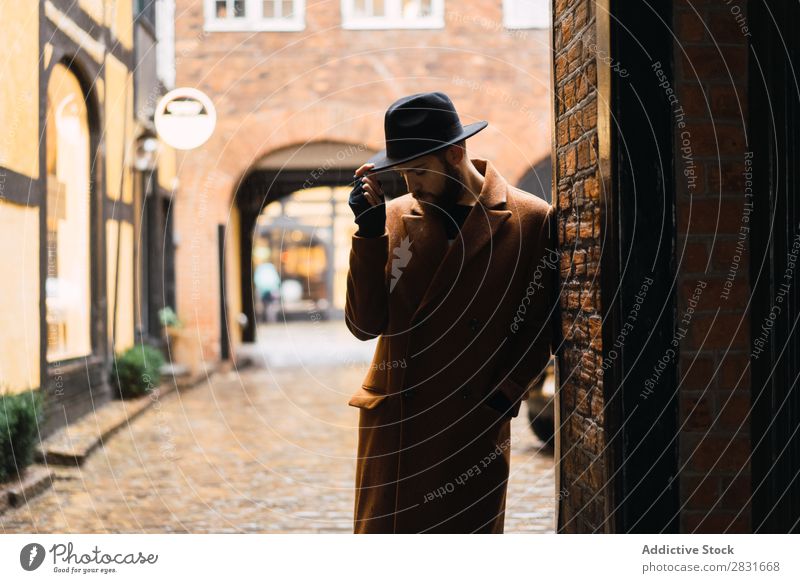 Stilvoller Mann, der sich an die Wand lehnt. gutaussehend Großstadt Mantel Hut anlehnen Straße Jugendliche Stadt Lifestyle lässig Mode Erwachsene modern Mensch