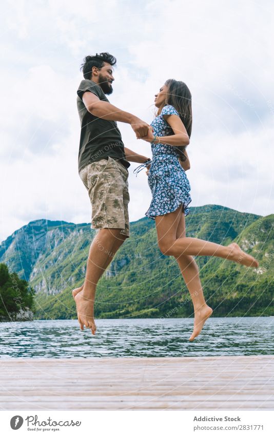 Paar Springen auf dem Pier Anlegestelle Freude See Berge u. Gebirge springen Glück Liebe Zusammensein Natur Sommer Wasser Jugendliche Frau