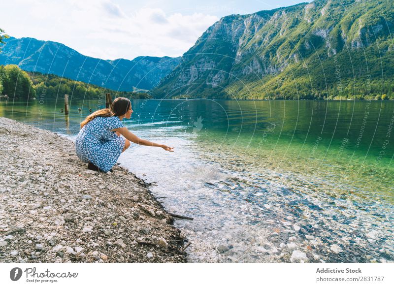 Frau am See sitzend Hand ziehend Küste Berge u. Gebirge Natur Sommer Wasser Jugendliche Ferien & Urlaub & Reisen Lifestyle Mensch schön Landschaft Mädchen