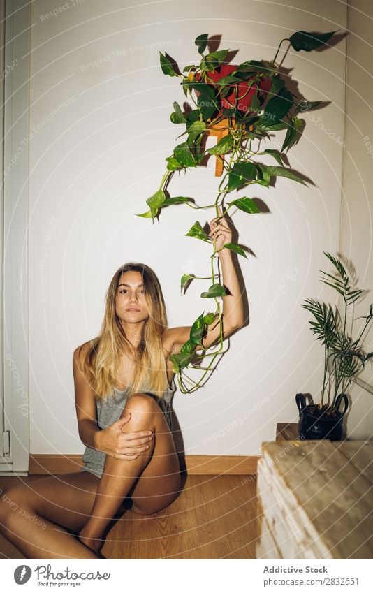 Frau mit Blume auf dem Boden genießen attraktiv sitzen Etage eingetopft Pflanze Körperhaltung heimwärts Beautyfotografie schön Jugendliche hübsch Mädchen