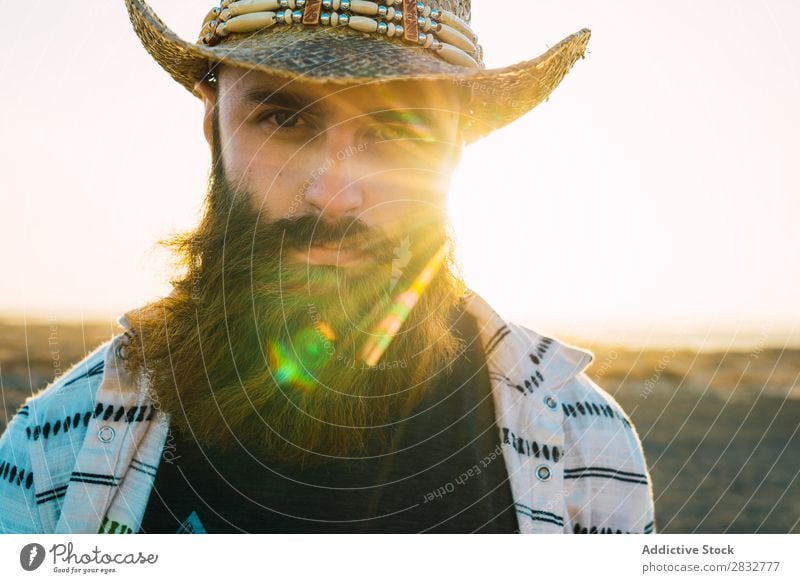 Bartiger Mann mit Hut gegen Sonnenlicht bärtig Cowboy Stil selbstbewußt Natur Porträt Länder maskulin ernst Strohhut Outfit Außenaufnahme Ausdruck Reisender