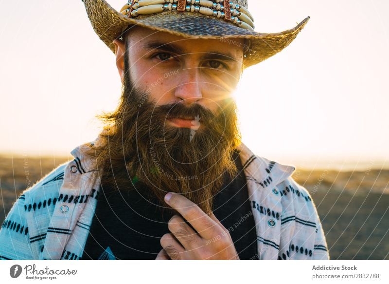 Bartiger Mann mit Hut gegen Sonnenlicht bärtig Cowboy Stil selbstbewußt Natur Porträt Länder maskulin ernst Strohhut Outfit Außenaufnahme Ausdruck Reisender