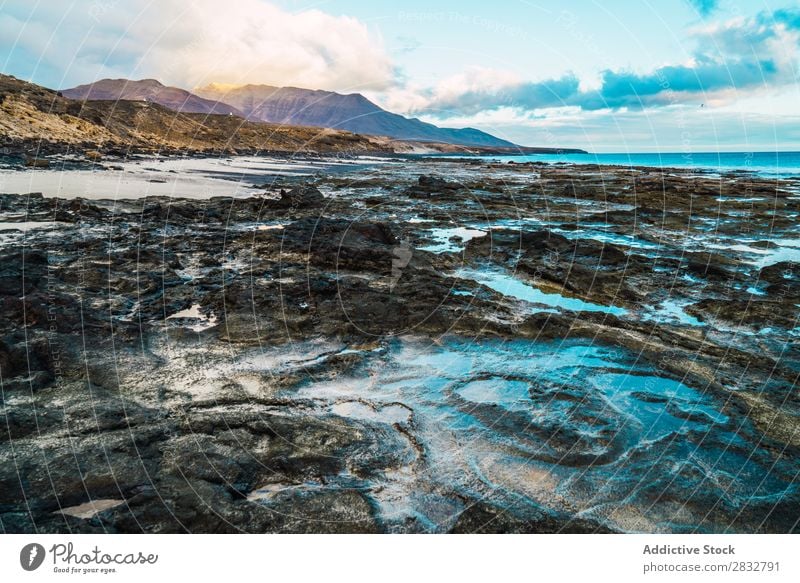 Erstaunliche Uferformationen mit Bergen im Hintergrund Küste Schlamm Formation Meer Landschaft schlammig Felsen Wildnis Beautyfotografie friedlich Strand