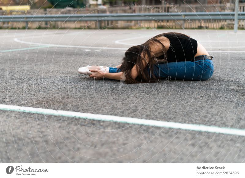 Frau, die auf einem Spielplatz liegt. Balletttänzer Tanzen lügen Boden Asphalt Pose Straße Entwurf Großstadt Stadt Mädchen Tänzer Ballerina elegant schön