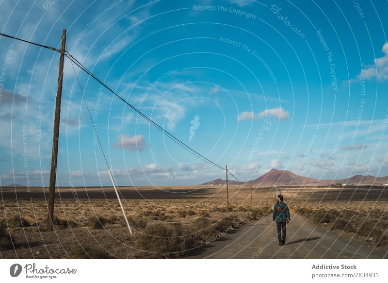 Mann, der auf der Straße im Feld geht. Tourist laufen Berge u. Gebirge regenarm Wolken Natur Landschaft natürlich Felsen Stein Lanzarote Spanien Aussicht