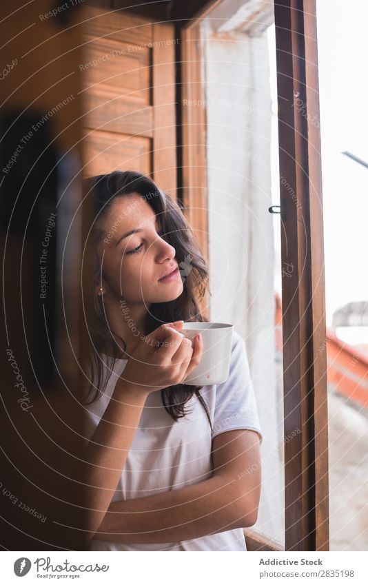 Junge hübsche Frau mit einer Tasse Fenster besinnlich träumen Fürsorge Blick Becher trinken schön Jugendliche Beautyfotografie Mädchen Tee Kaffee heimwärts