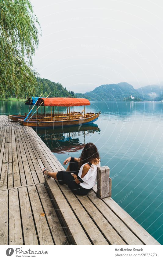 Frau, die auf die Hügel am See schaut. sitzen Anlegestelle Berge u. Gebirge Küste Aussicht Natur Wasser Landschaft Sommer blau grün schön Szene