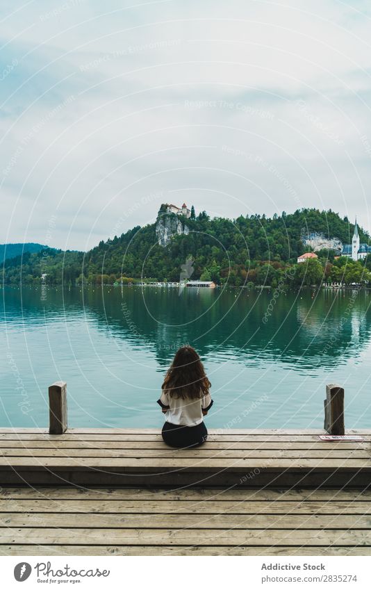 Frau, die auf die Hügel am See schaut. sitzen Anlegestelle Berge u. Gebirge Küste Aussicht Natur Wasser Landschaft Sommer blau grün schön Szene