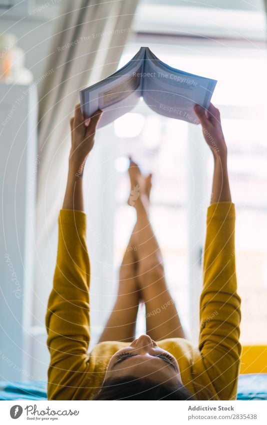 Hübsche Frau, die mit Buch lügt. hübsch heimwärts Jugendliche lügen lesen Roman Literatur Körperhaltung Porträt schön Lifestyle Beautyfotografie attraktiv Dame