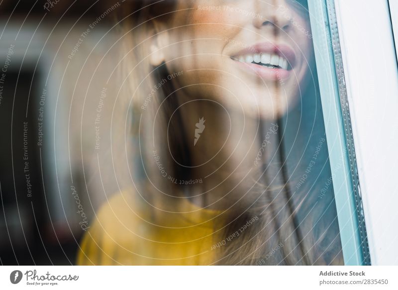 Beschneiden Sie die fröhliche Frau am Fenster. hübsch heimwärts Jugendliche durch das Fenster Lächeln heiter Glück Körperhaltung Porträt schön Lifestyle