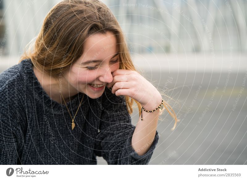 Fröhlich lachendes junges Mädchen Frau hübsch Porträt Jugendliche schön Blick in die Kamera berühren Wange heiter Lächeln Glück Pullover lässig Gesicht