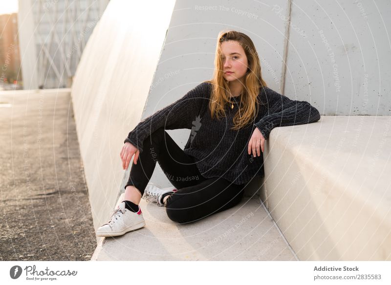 Außenportrait eines jungen Mädchens auf einer Betontreppe mit Blick in die Kamera. Frau Sitzen Klotz Treppe Gebäude verträumt nachdenklich besinnlich