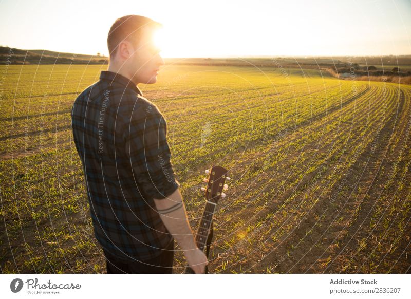 Mann mit Gitarre auf dem Feld Natur Musik stehen Lifestyle Musiker lässig Gitarrenspieler akustisch grün laufen Musical Mensch Typ natürlich Instrument Spielen