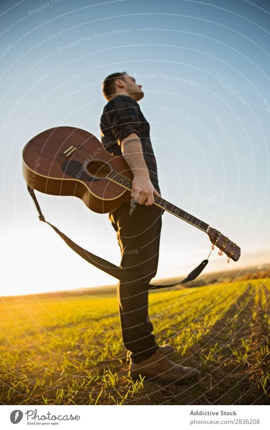 Mann mit Gitarre auf dem Feld Natur Musik stehen Lifestyle Musiker lässig Gitarrenspieler akustisch grün laufen Musical Mensch Typ natürlich Instrument Spielen