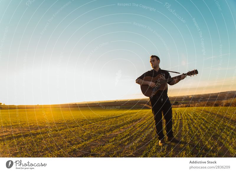 Mann mit Gitarre auf dem Feld Natur Musik stehen Lifestyle Musiker lässig Gitarrenspieler akustisch grün laufen Musical Mensch Typ natürlich Instrument Spielen