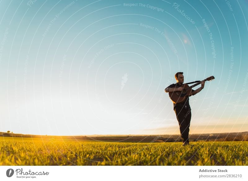 Mann mit Gitarre auf dem Feld Natur Musik stehen Lifestyle Musiker lässig Gitarrenspieler akustisch grün laufen Musical Mensch Typ natürlich Instrument Spielen