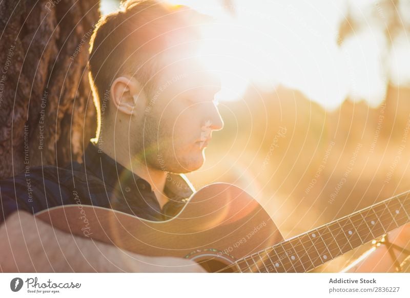 Mann spielt Gitarre in der Natur Musik Wald Sonnenstrahlen Tag anlehnen sitzen Rüssel Lifestyle Musiker lässig Gitarrenspieler akustisch Herbst Musical Mensch