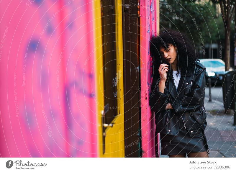 Glamouröse Frau an rosa Wand attraktiv Großstadt modisch lockig anlehnen brünett Jacke Mode Jugendliche schön hübsch Straße Model Stil Behaarung