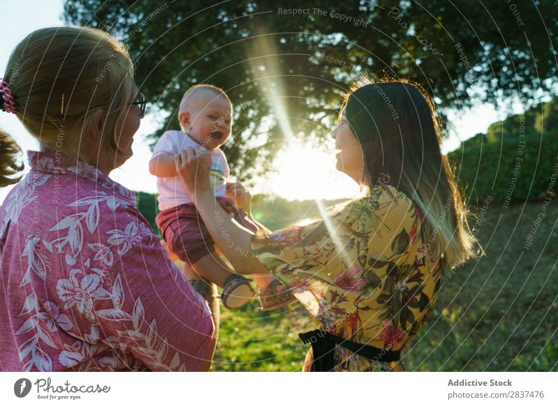 Glückliches lesbisches Paar mit Kind Mutter Park grün Sonnenstrahlen Mensch Frau Fröhlichkeit Sommer Lifestyle Liebe gleichgeschlechtliche Eltern Homosexualität